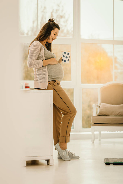 Pregnant woman staying at home and drinking tea - Foto, afbeelding