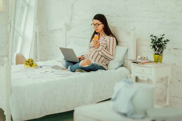 Pregnant woman drinking a juice and working remotely - Foto, Bild