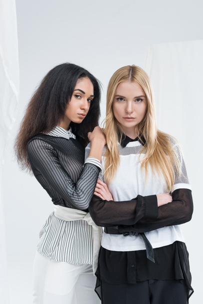 attractive multiethnic women in black and white clothes standing and looking at camera together isolated on white - Φωτογραφία, εικόνα