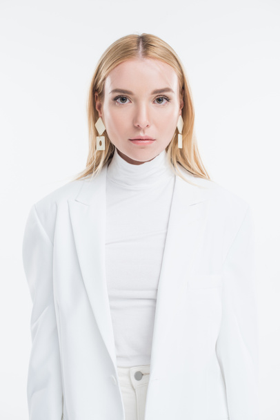 portrait of attractive caucasian blonde woman in fashionable white clothes and earrings looking at camera isolated on white - Fotoğraf, Görsel
