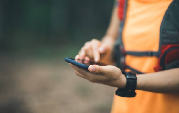 Sportswoman trail runner using smartphone for navigation in forest - Foto, afbeelding