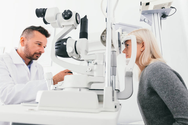 Opticien controleren vrouw gezichtsvermogen met speciale apparatuur. Geneeskunde, gezondheidszorg. - Foto, afbeelding