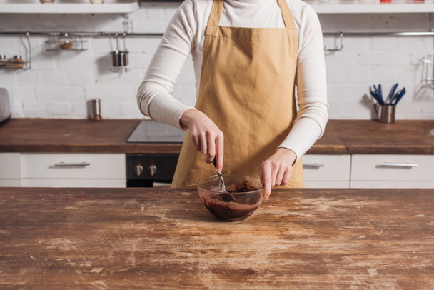 cropped shot of woman in apron preparing dough for gourmet homemade cake in kitchen   - Foto, Bild