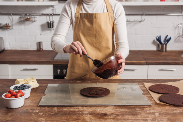 cropped shot of woman in apron preparing dough for gourmet homemade cake in kitchen   - Foto, Bild