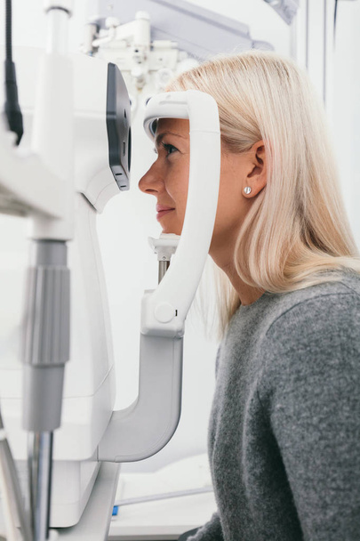 Kobieta robi test wzroku w gabinecie optycznym. Opieka zdrowotna, leczenie oczu. - Zdjęcie, obraz