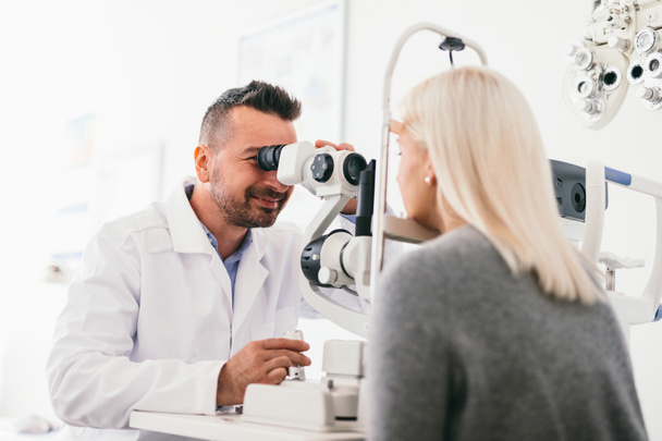 Augenoptiker, der die Augen der Frau mit einem Gerät untersucht. Augenpflege, Arzttermin. - Foto, Bild