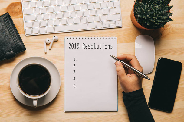 2019 ψηφίσματα - κείμενο σε σημειωματάριο στο χώρο εργασίας το top view, λίστα ελέγχου ή σχέδιο της επιχειρηματικής στρατηγικής για κίνητρα και έμπνευση - Φωτογραφία, εικόνα