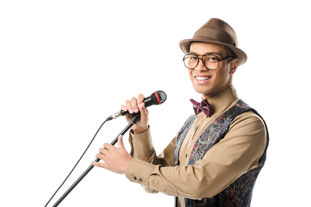szczęśliwy młody muzyk mężczyzna w kapeluszu i śpiewając w mikrofon na białym tle okulary - Zdjęcie, obraz