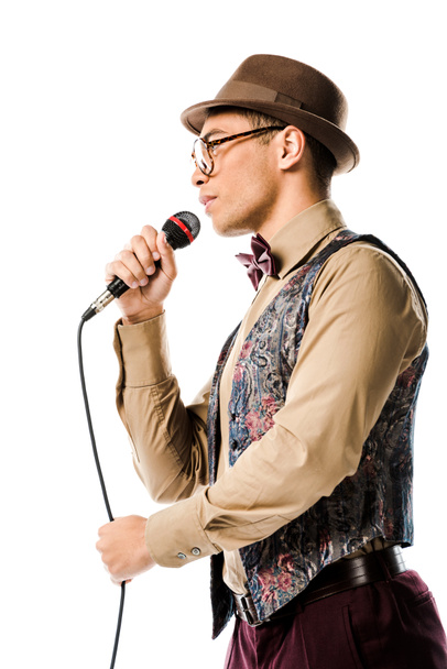 vista de bajo ángulo del músico masculino de raza mixta en sombrero cantando en micrófono aislado en blanco
 - Foto, Imagen