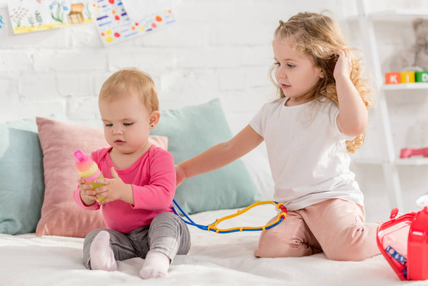 adorable children playing with first aid kit in children room - Photo, image