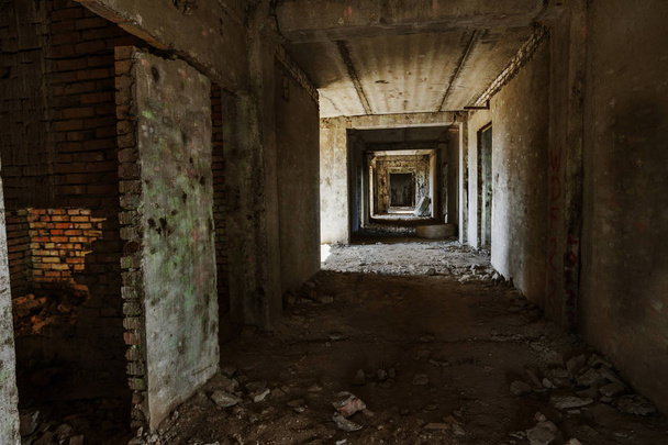 Interior de un edificio administrativo abandonado. Ruinas interiores de una fábrica industrial. Una vieja escalera de hormigón, ruinas, pasillo con basura y barro, paredes arruinadas de un centro de negocios de oficinas sin terminar, Odessa
 - Foto, imagen