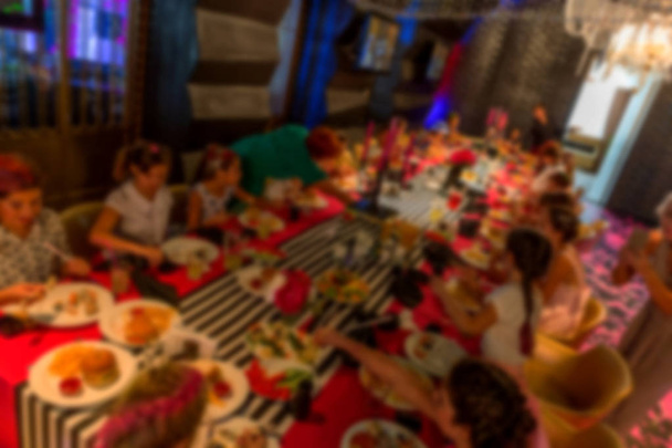 Blurred bokeh cafe interior in dark colors. As a background for creative fashion design. Restaurant, cafe with a beautiful background blur bokeh. Blurring background banquet table with the visitors in dim light - Photo, Image