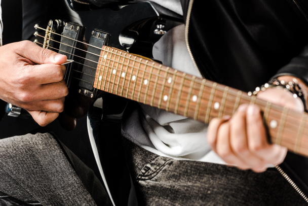 vista parcial del músico de rock masculino en chaqueta de cuero tocando en la guitarra eléctrica aislado en blanco
 - Foto, Imagen