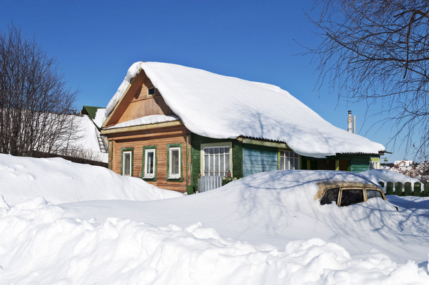 Wooden house and a car in snow drifts - Fotoğraf, Görsel