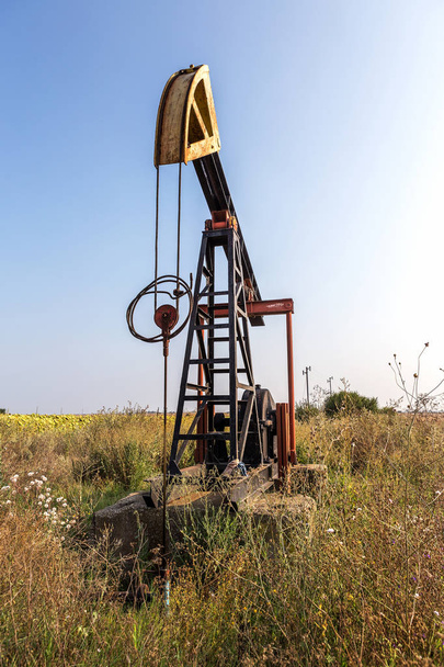 Un petit derrick pétrolier privé pompe l'huile sur le terrain. La vieille plate-forme pétrolière artisanale dans le fond du design industriel créatif. Développement illégal de minéraux. Bulgarie Tyulenovo, 2016
 - Photo, image
