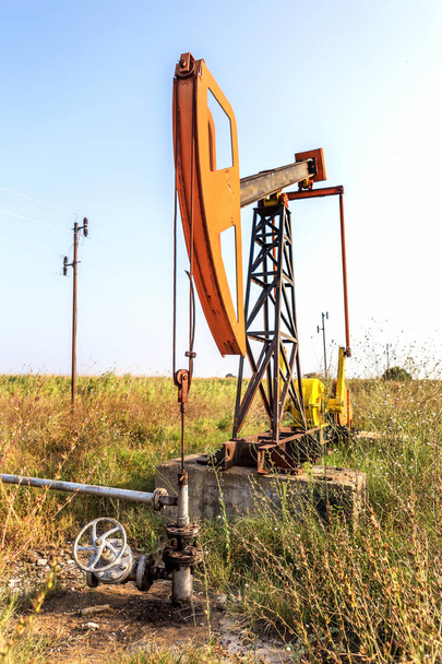 Ένα μικρό ιδιωτικό πετρελαίου derrick αντλίες πετρελαίου στο πεδίο. Παλιά εξέδρα πετρελαίου χειροτεχνίας στο παρασκήνιο την δημιουργική βιομηχανικού σχεδιασμού. Παράνομη ανάπτυξη των ορυκτών. Βουλγαρία στο Tyulenovo, 2016 - Φωτογραφία, εικόνα