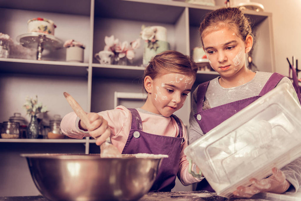 Delighted cute girl cooking together with her friend - Foto, imagen