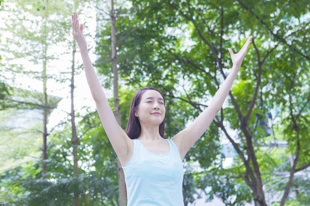 Giovane donna asiatica in piedi nel bosco braccia aperte e sorridenti con gli occhi chiusi
 - Foto, immagini
