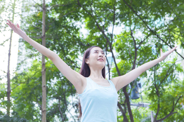 Młoda kobieta azjatyckich stojących w otwarte ramiona lasy i uśmiechem, patrząc od - Zdjęcie, obraz