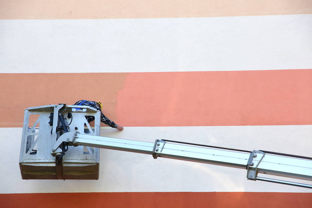 Painting the facade from at a height using a special jib. - Foto, afbeelding