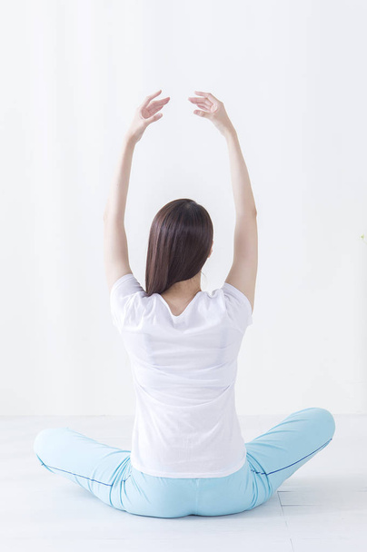 Young Asian woman stretching herself and showing her back to the camera - Photo, Image