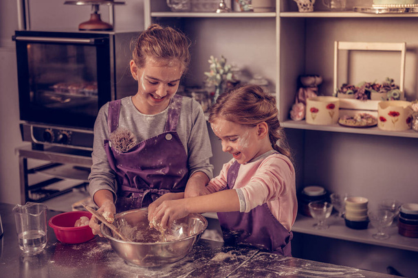 Joyful positive sisters having fun while cooking - Fotoğraf, Görsel