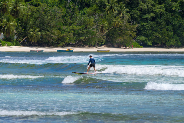 MAHE, SEYCHELLES - SEPTEMBER 25, 2018: Unidentified man surfing on a large wave on island Mahe  on the coast of Indian ocean - is the best surf paradise in Seychelles - Φωτογραφία, εικόνα