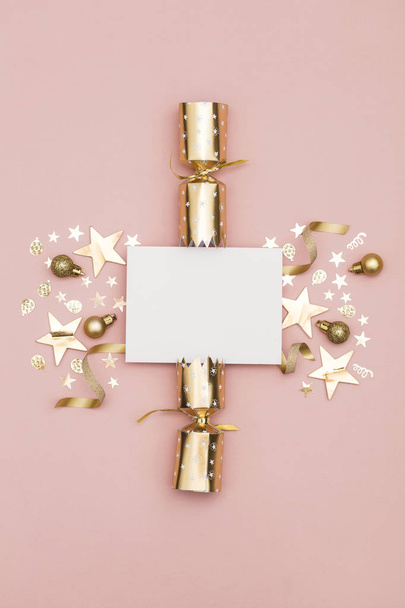Gold Christmas cracker with a blank white label. luxury gold festive cracker on a pastel pink background - Photo, image