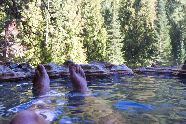piscines minérales chaudes relaxantes entourées par la forêt dans les montagnes de l'Oregon avec mes pieds dans le cadre poussant mon point de vue
 - Photo, image