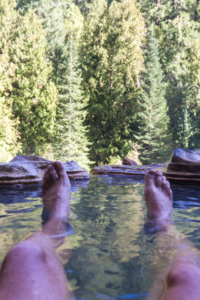 relaxing hot mineral pools surrounded by forest in the mountains of Oregon with my feet in the frame shoving my point of view - Photo, Image