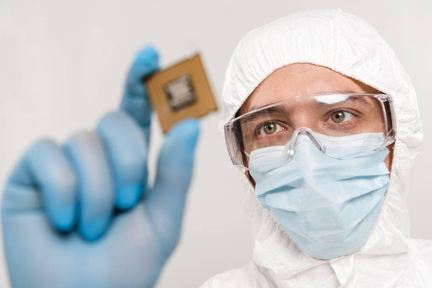 selective focus of scientist looking at microchip in latex glove isolated on grey - Photo, Image