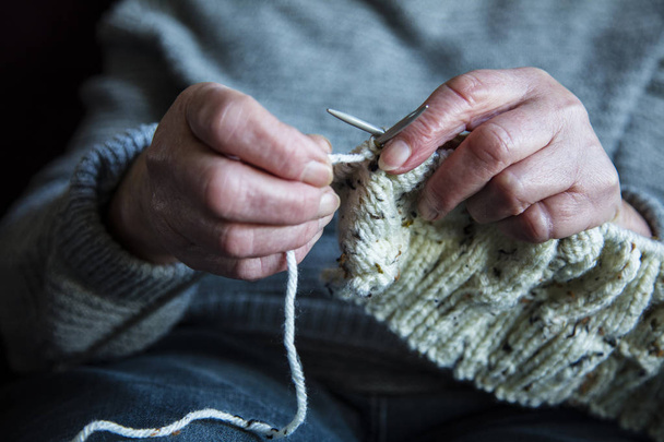 Close up of an older womens hands knitting a jumper - Photo, image