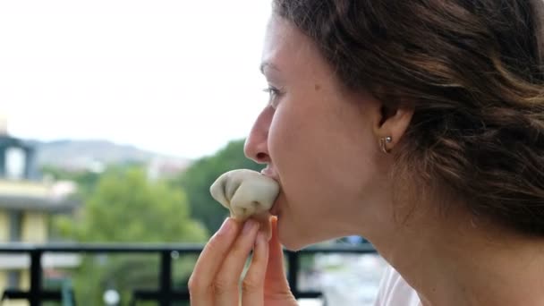 Portret van een vrouw die het eten van khinkali of dumplings met een close-up van de hand - Video