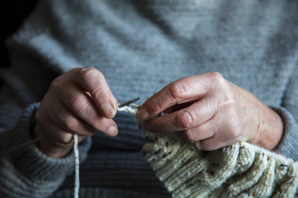 Close up of an older womens hands knitting a jumper - Photo, image