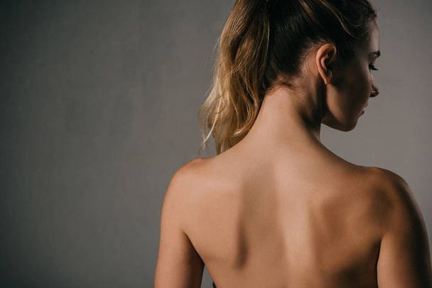 back view of woman with ponytail on grey background - Valokuva, kuva
