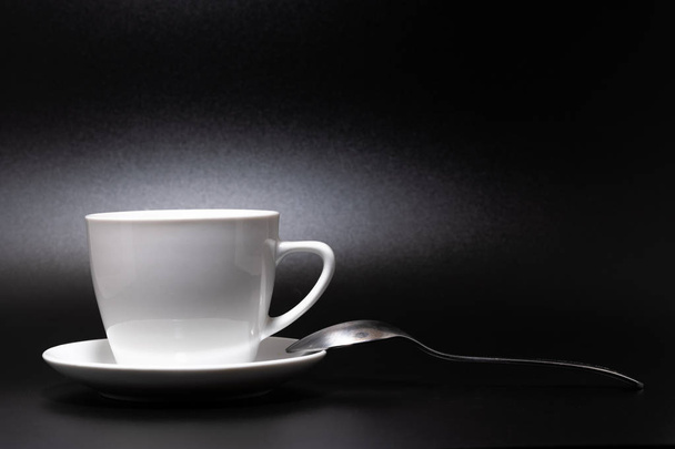 White cup, saucer and spoon on a black background 2018 - Zdjęcie, obraz