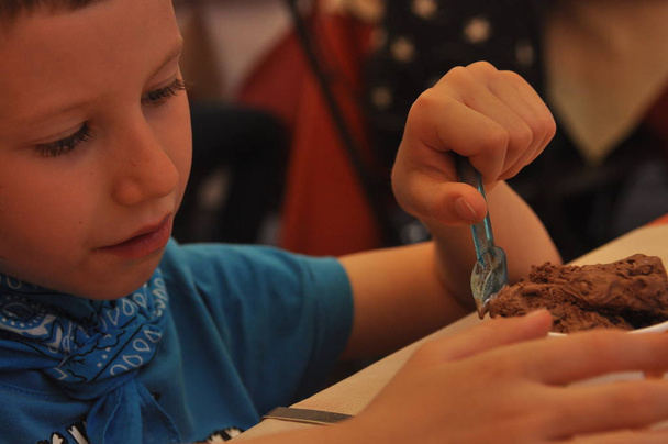 Egy fiú, egy kék póló eszik csokoládé fagylalt, egy étteremben - Fotó, kép