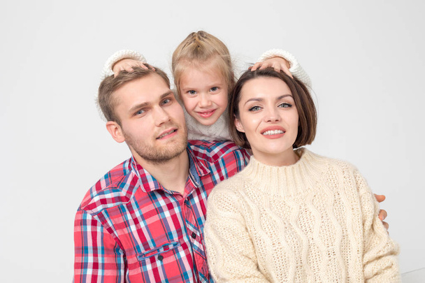 glückliche dreiköpfige Familie umarmt sich auf weißem Hintergrund. - Foto, Bild