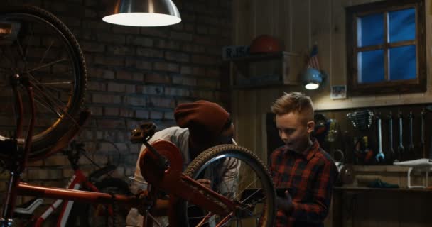 Человек учит мальчика техническому обслуживанию велосипедов
 - Кадры, видео