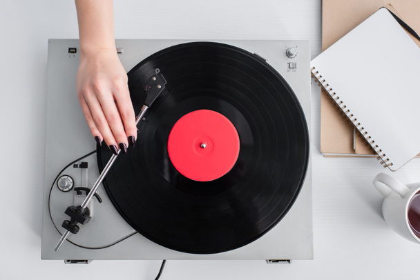 cropped view of woman playing vinyl record on vintage player - Foto, Imagen
