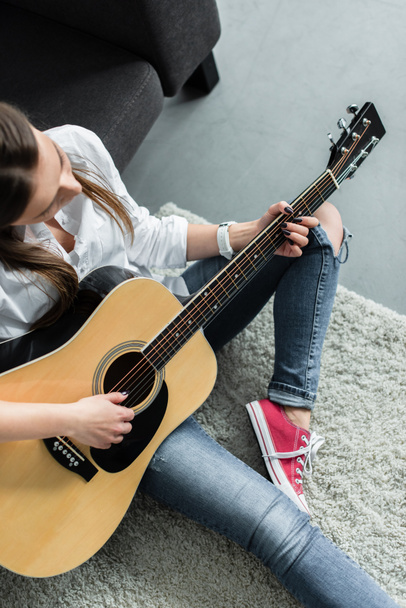 partial view of girl sitting and playing guitar in living room - Φωτογραφία, εικόνα