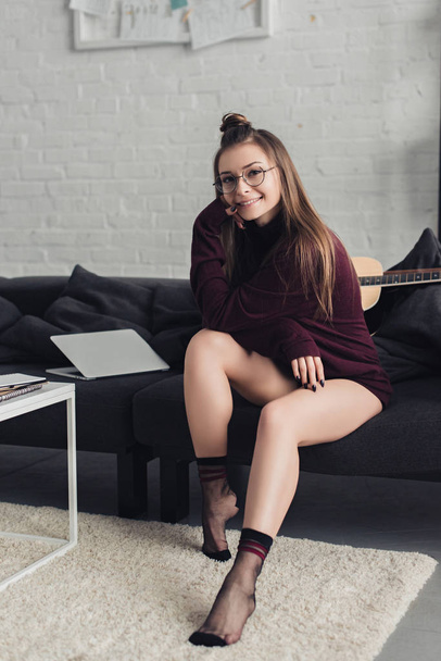 beautiful girl looking at camera and sitting on couch in living room - Foto, Bild