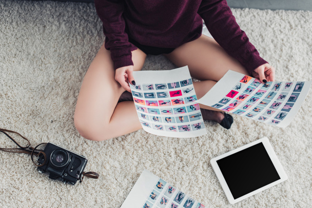 cropped view of photographer sitting on carpet and holding pictures - Photo, Image