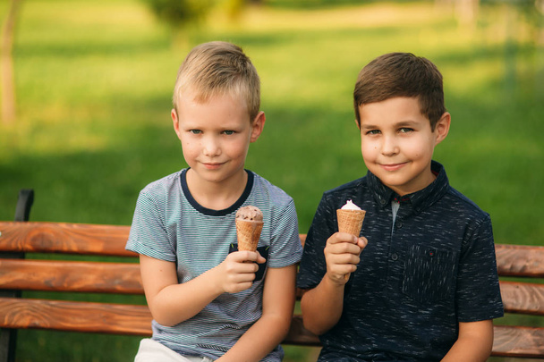 Les enfants sont assis sur le banc et mangent de la glace
 - Photo, image