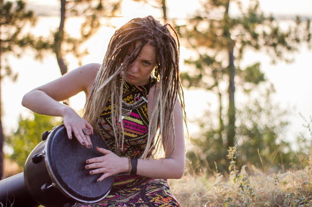 hermosa mujer joven hippie chamán jugando djembe y bailando bailes salvajes al atardecer
 - Foto, imagen