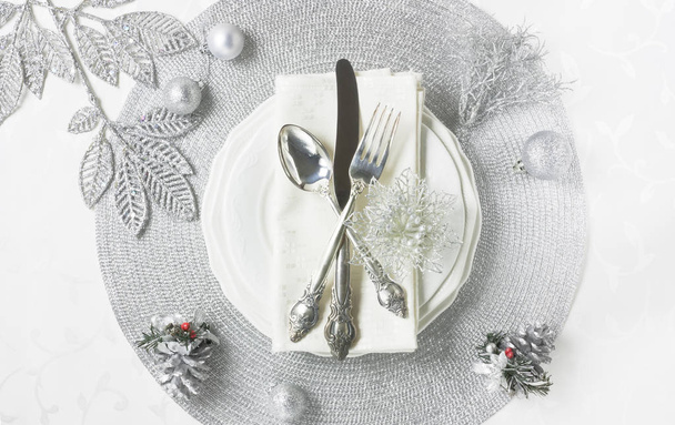 Stříbrná vánoční stůl nastavení s dekoracemi, talíře, příbory na bílém stole pro dovolenou večeři - Fotografie, Obrázek