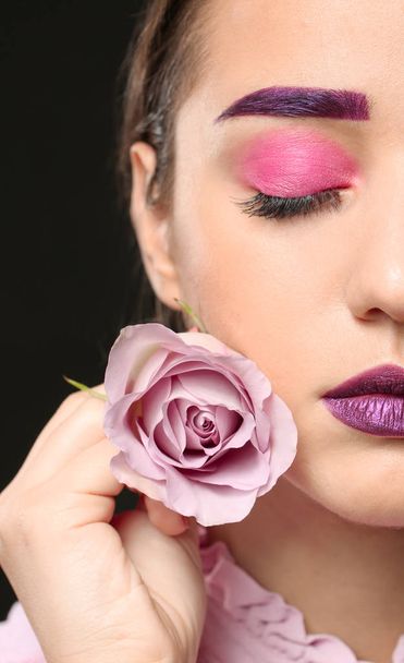 Young woman with dyed eyebrows and creative makeup on dark background - Foto, Bild