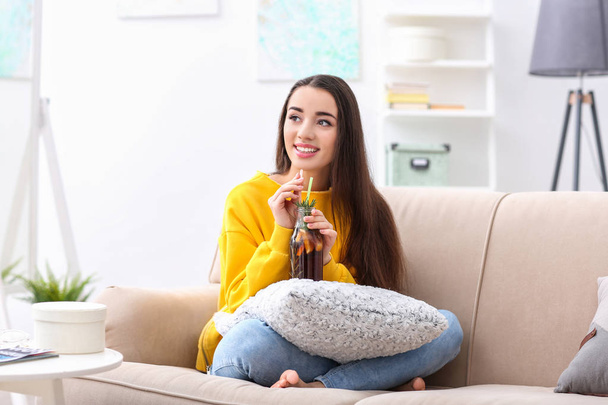 Young woman with tasty refreshing lemonade indoors - 写真・画像