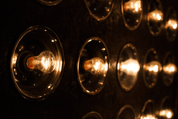 Lâmpadas incandescentes elétricas de ouro brilhante vintage em um fundo preto. holofotes modernos como um item interior. Close-up
 - Foto, Imagem