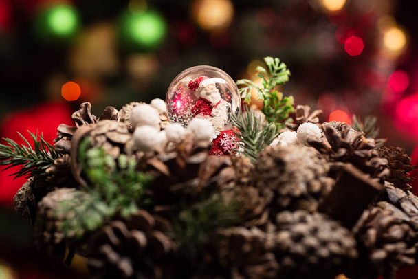 Fondo de Navidad. Santa Claus en una pelota con nieve artificial. Árbol de Navidad y decoraciones. Nochebuena. Fondo borroso con bokeh. Conos de abeto. Feliz Año Nuevo
 - Foto, imagen